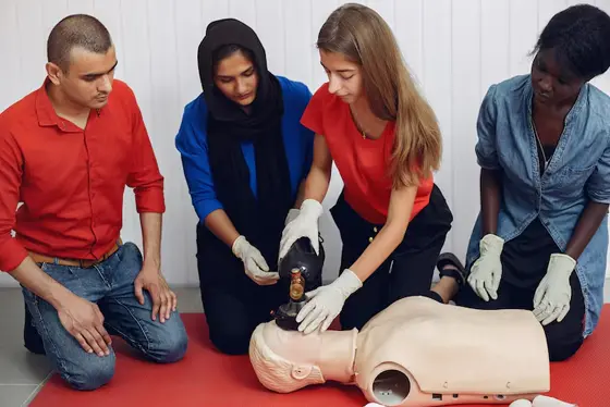 Learner wrapping gauze bandage around volunteer’s forearm during first aid class