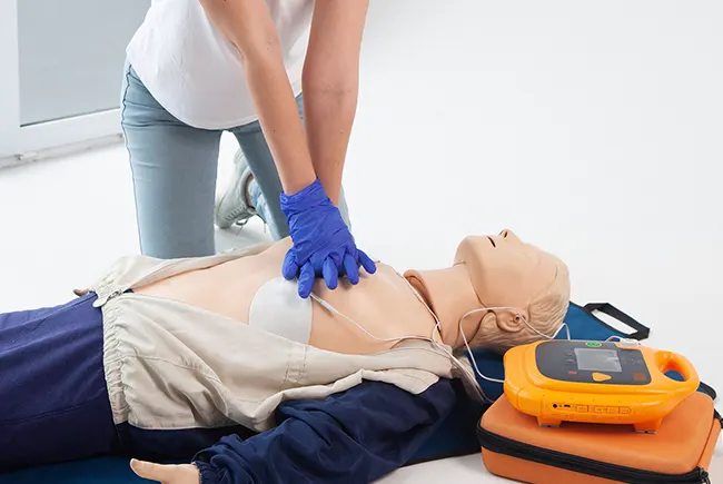 Instructor demonstrating AED pad placement on torso mannequin during training session